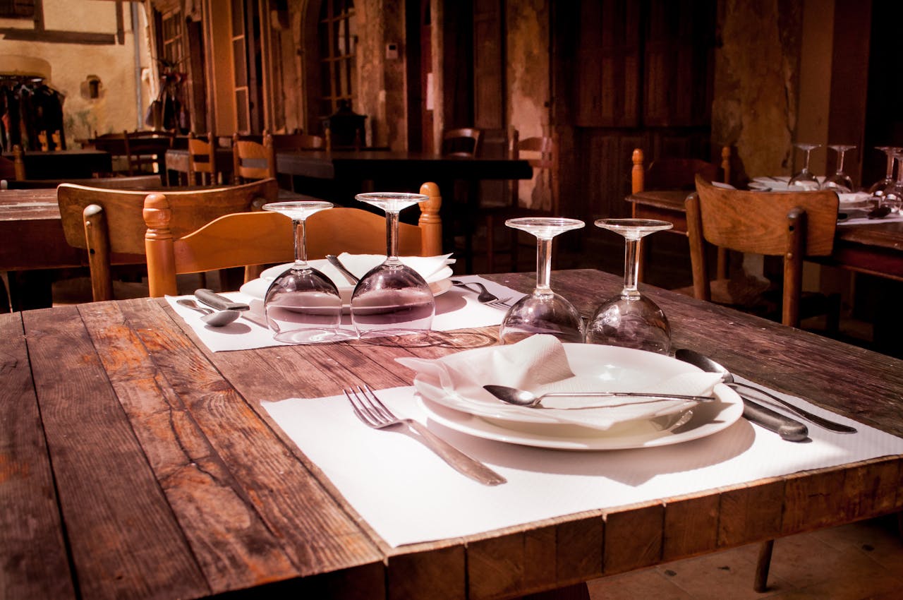 A rustic restaurant table set with wine glasses and cutlery invites guests to dine.