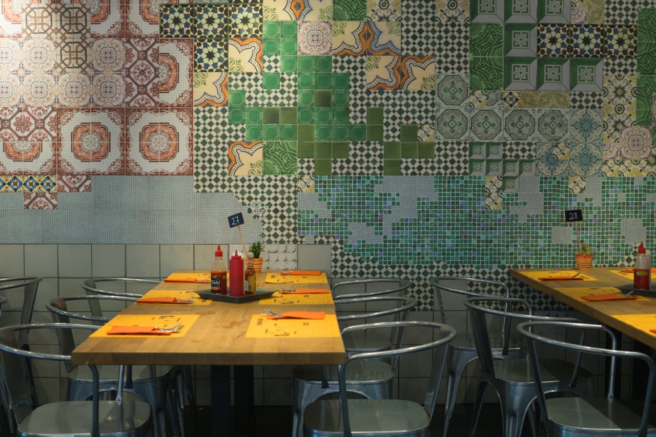 Vibrant restaurant interior featuring colorful tiled walls and neatly arranged dining tables.